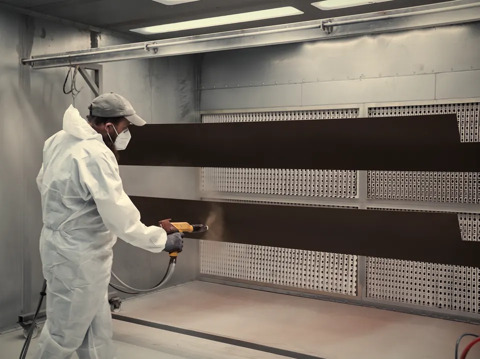 Staff member powder coating a long panel